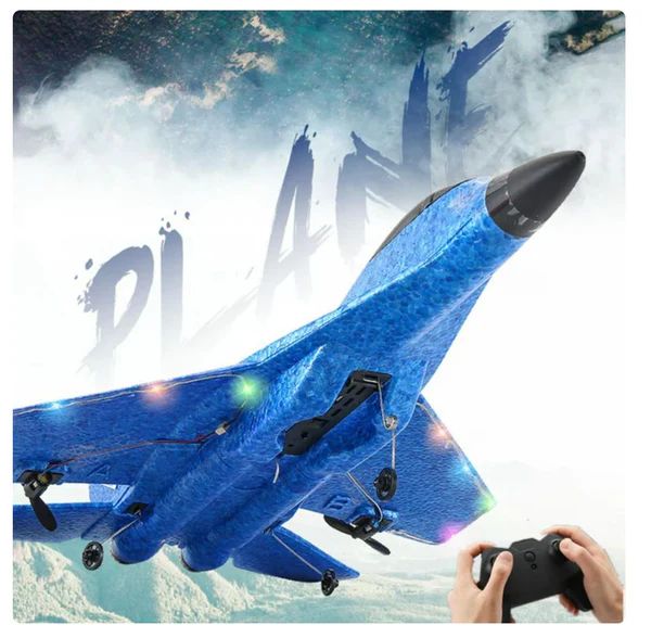 Blue toy airplane with remote control held by a hand against a mountainous background